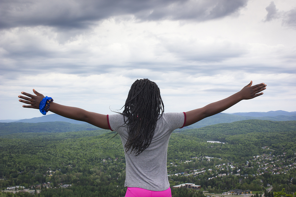 Child with Arms Outstretched on top Mountain