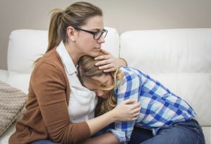 Mother embracing and soothes depressed daughter