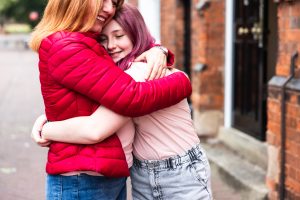 Woman and girl giving lovely hug and smiling