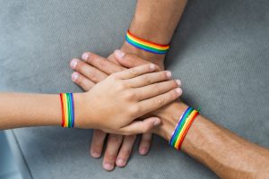 Three hands with pride bracelets. 
