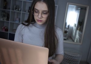 young girl with glasses holding laptop